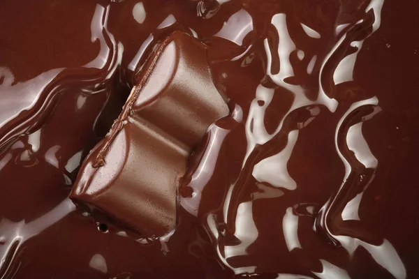 Розтоплений шоколад і шматочки шоколадного бару як фон крупним планом — стокове фото