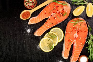Dilim limon ile kırmızı balık somon, biberiye, metniniz için kopya alanı siyah taş zemin üzerine. Üstten Görünüm