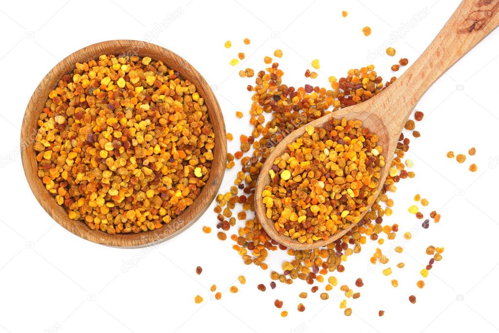 fresh bee pollen in wooden spoon and bowl isolated on white background. Top view. Flat lay