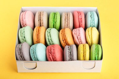 kutusunda sarı beyaz arka plan üzerinde renkli macarons