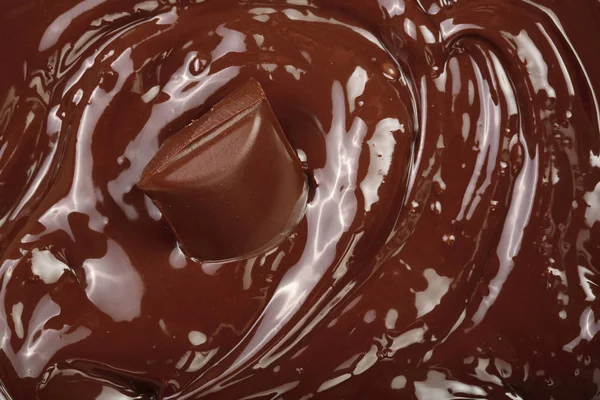 Розтоплений шоколад і шматочки шоколадного бару як фон крупним планом — стокове фото