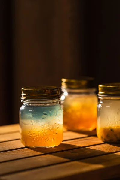 jar of honey and a glass of water on a wooden table