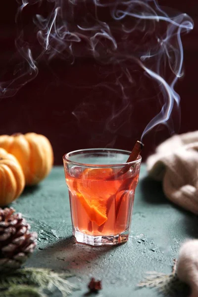 halloween pumpkin drink with orange juice and cinnamon on dark background