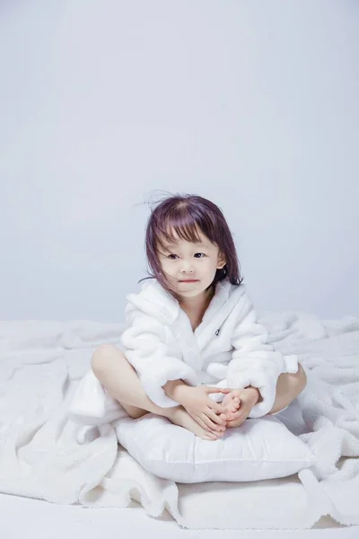 little girl in white dress and sleep mask on bed