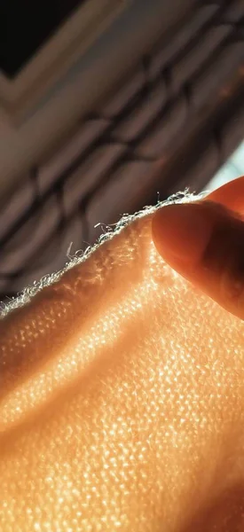 close up of a female hand with a feather on a black background