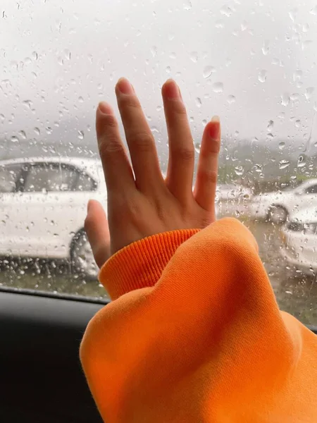 woman washing her car with rain drops on the window