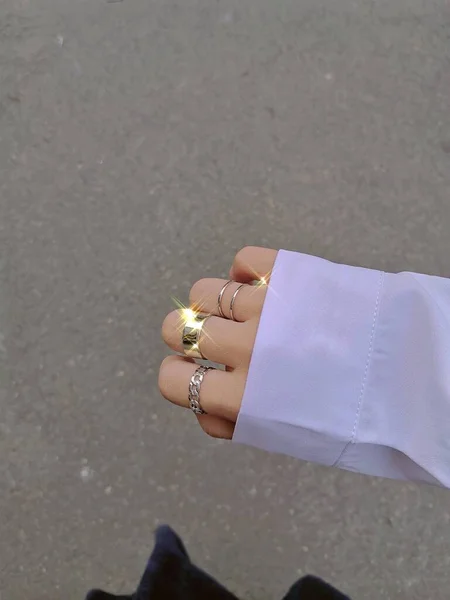 hand holding a white diamond ring on a background of a female hands