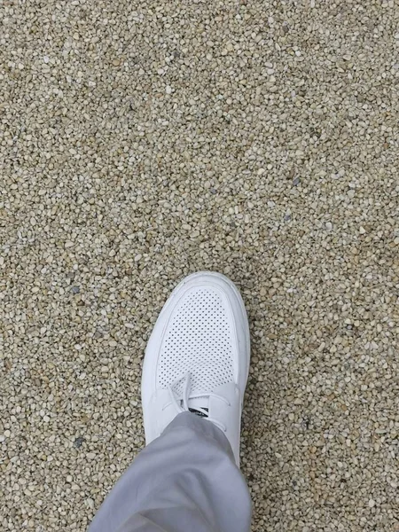 feet of a man in a sneakers on the road