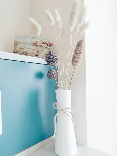 white vase with dried flowers on a light background