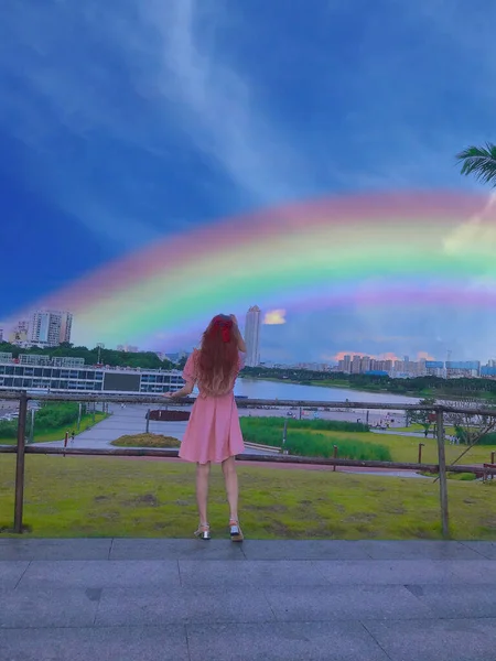 girl in a dress with a rainbow in the background of the city