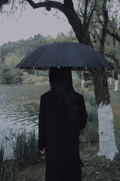 woman in a black dress with umbrella in the park
