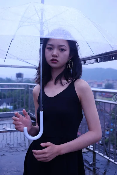 young beautiful woman in a black dress with umbrella