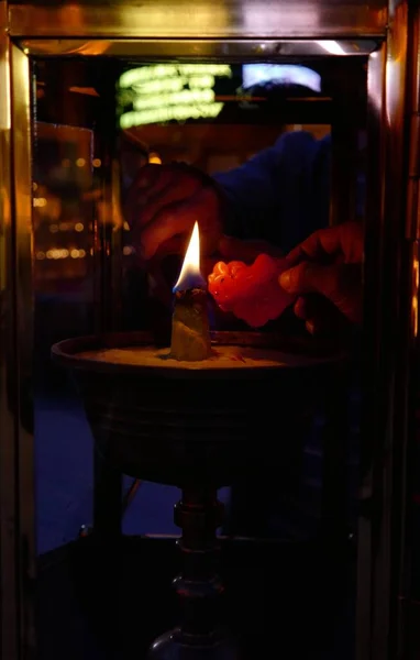 a man in a white robe with a candle in the background