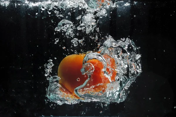 orange apple in water splash on black background
