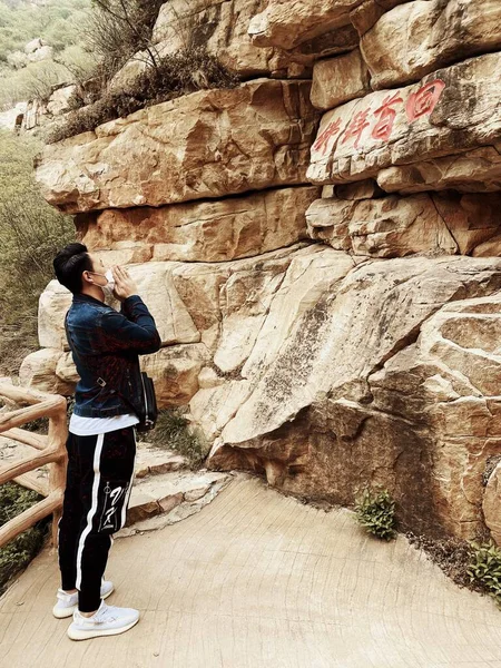 man in a jacket and jeans with a backpack on the background of the mountains