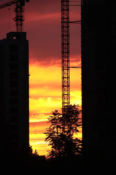 silhouette of a building with a crane on the background of the city