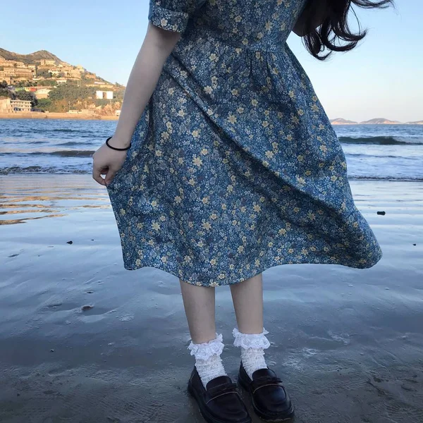 young woman in a dress with a bag on the beach