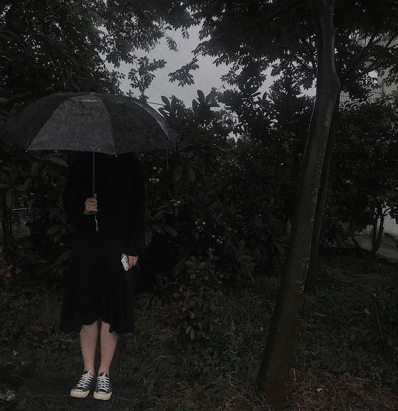 young woman in black dress with umbrella in the park