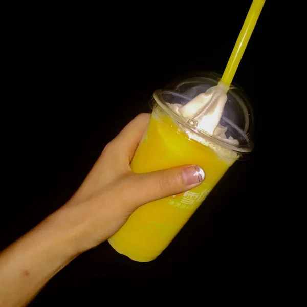 hand holding a glass of lemon juice on a black background