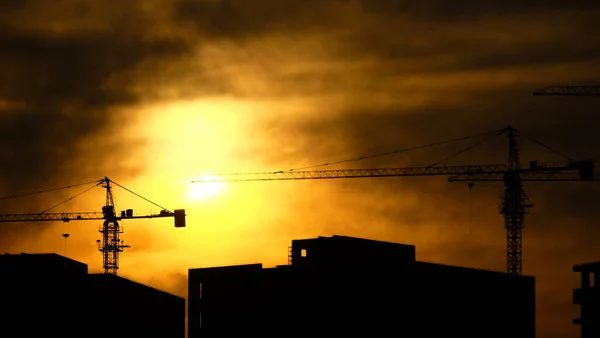 silhouette of a building cranes on a background of the sky