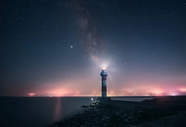 lighthouse at night, illuminated by the sea