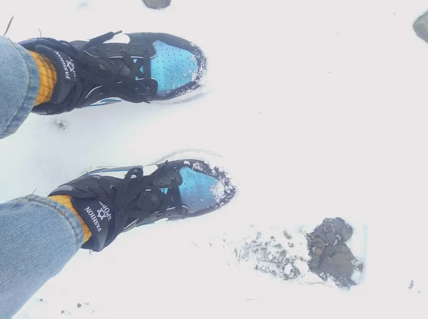 man\'s feet with a snowboard on the background of the ice.