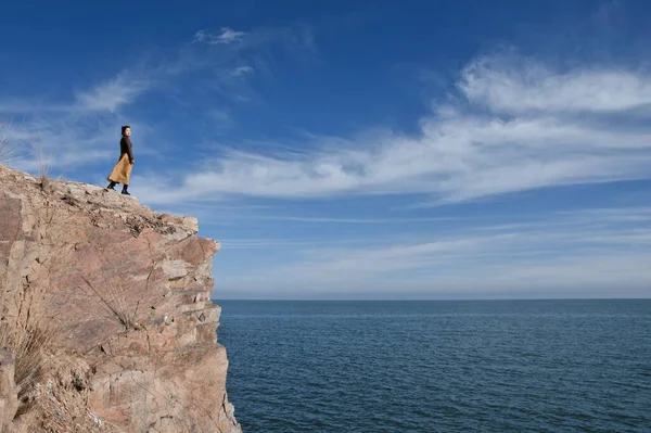 a man stands on the top of the cliff on the coast of the sea.