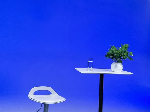 blue lamp on a table with a chair and a plant