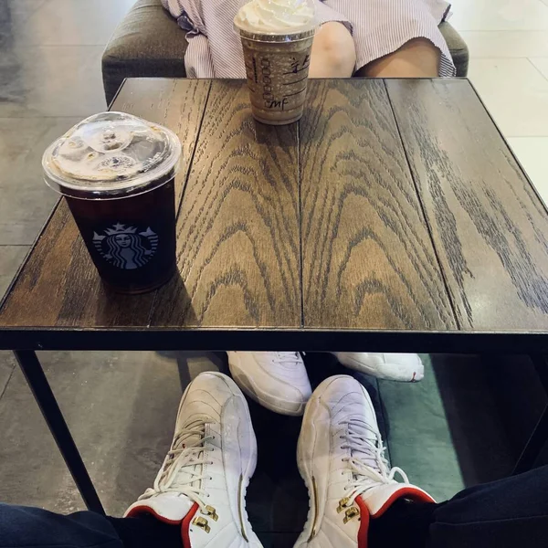 woman sitting on bench and drinking coffee and looking at the camera