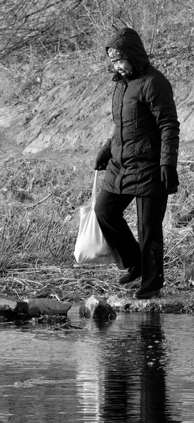 young woman in black and white with a backpack and a bag of water