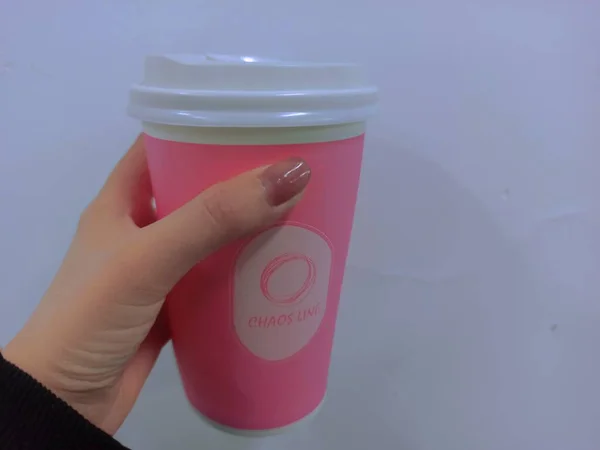 hand holding a disposable cup of coffee on a white background