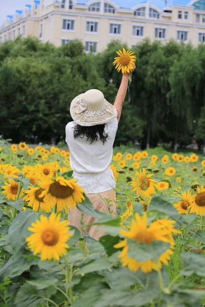 young woman in a hat with a bouquet of sunflowers