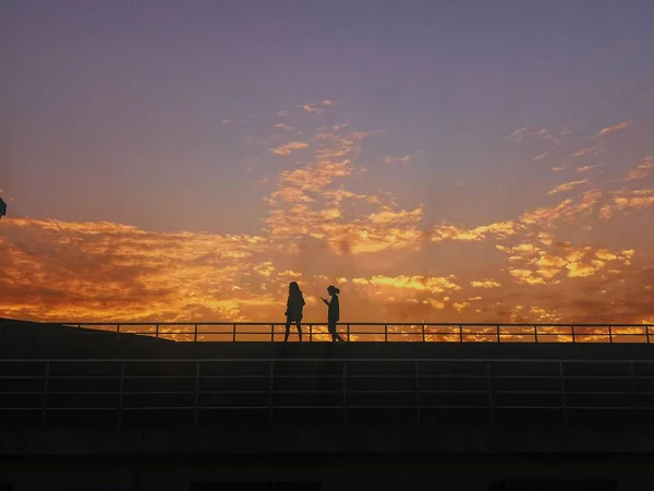 silhouette of a man and woman on the roof of the building