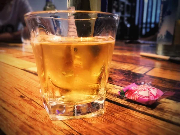 glass of whiskey with ice and salt on wooden table