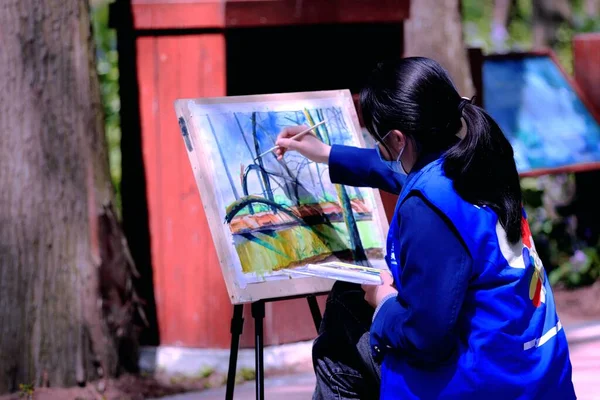 young woman painting a picture of a girl