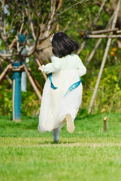 a girl in a white shirt and a blue dress with a dog in the park