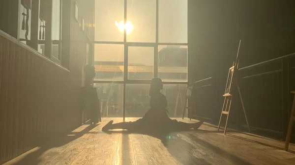 silhouette of a man sitting on the floor and looking at the camera