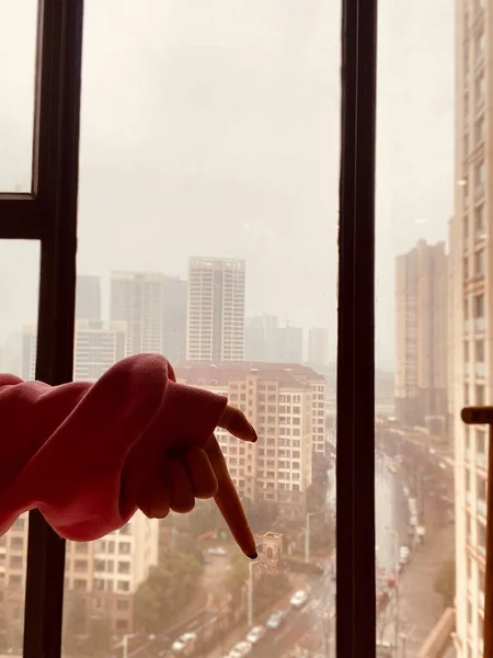 woman hand with window glass on background of building