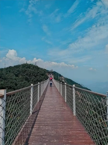 a man is walking on the bridge in the mountains