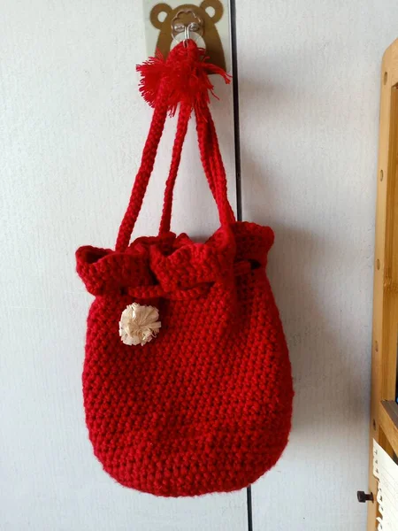 red knitted scarf and a bag of wool on a white background