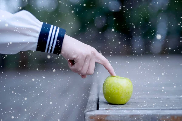 hand holding a green apple on a background of a blue sky