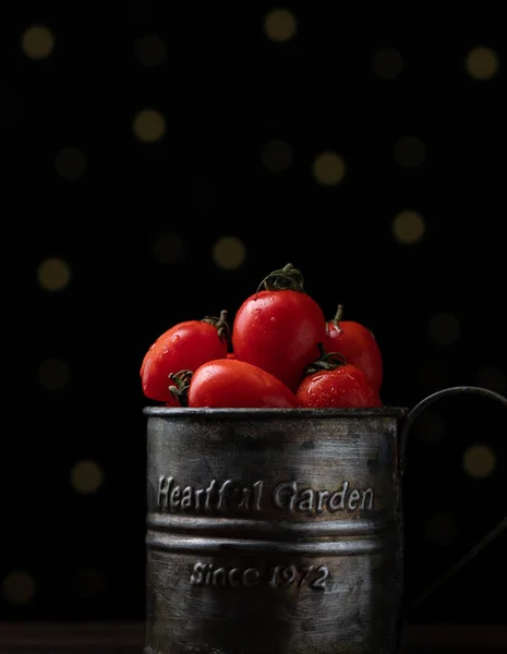 red and black tomatoes in a glass bowl on a dark background