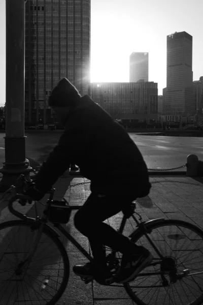 black and white photo of a young man in a suit and a bicycle on the background of the city