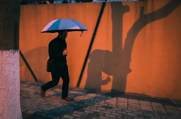 silhouette of a man in a rain coat and a woman in a rainy day