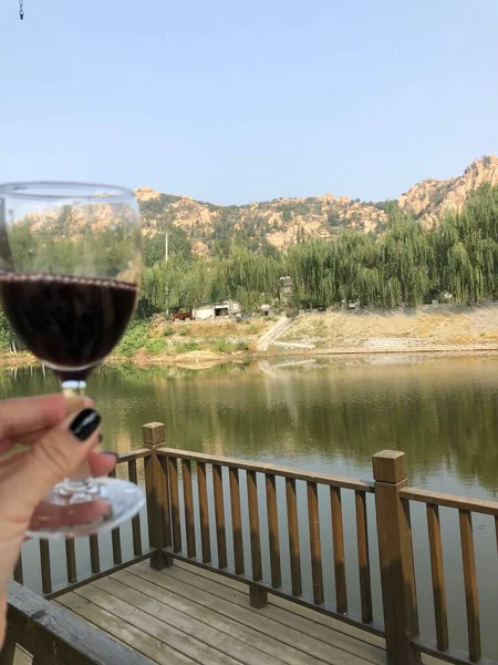 a glass of wine and a lake in the mountains