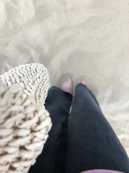 feet of a woman in a knitted sweater and socks on the beach