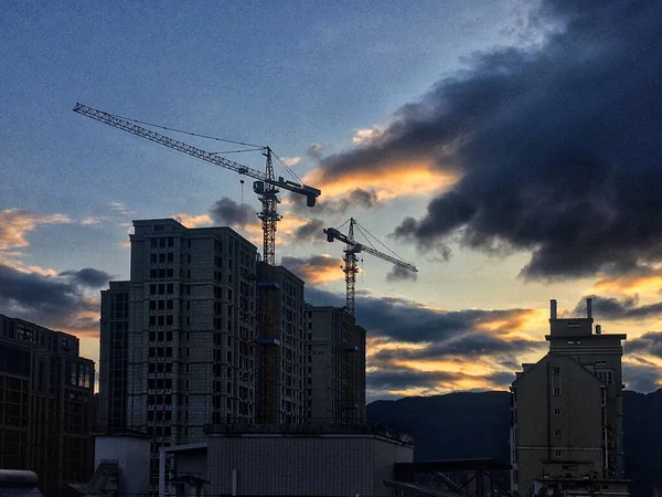 silhouette of a building with a crane and a skyscraper