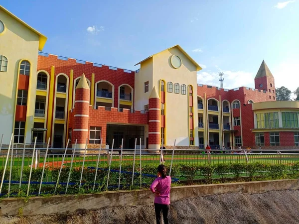 the girl is standing in the city of the university of the building in the background of the house