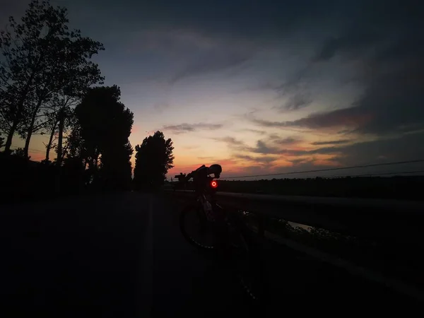 silhouette of a man riding a bike on the road