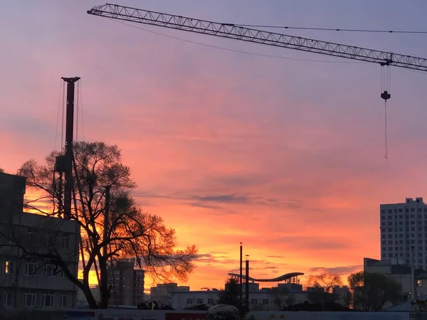 construction cranes and building under the sunset sky